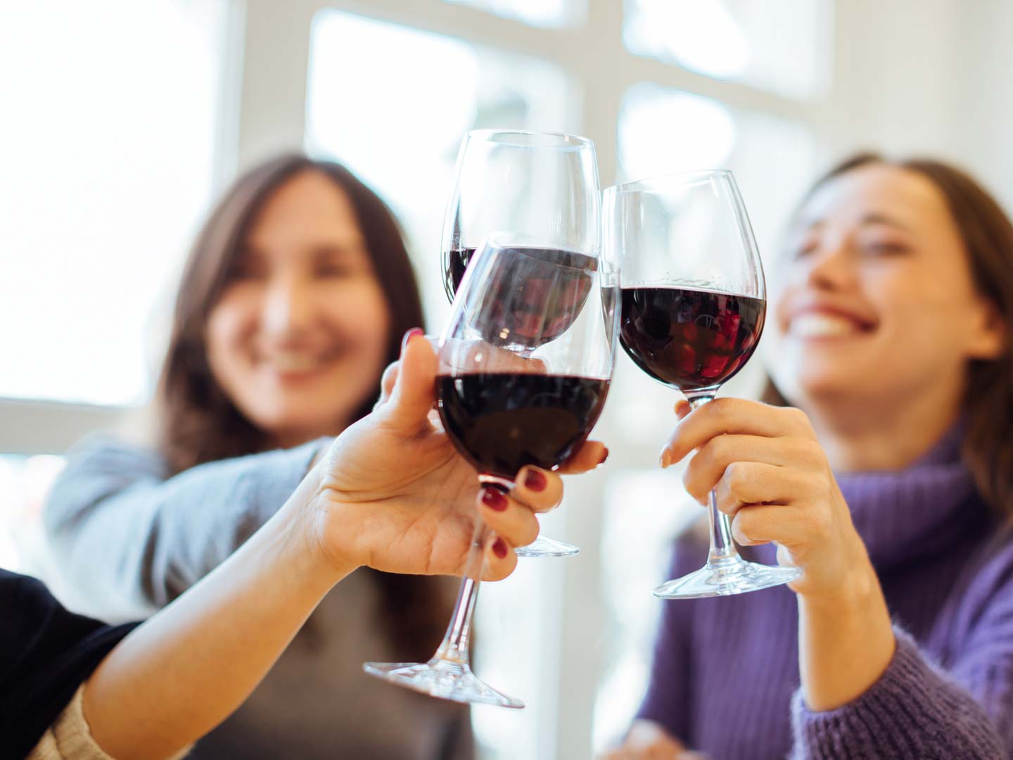 group of girls sharing red wine and celebrating