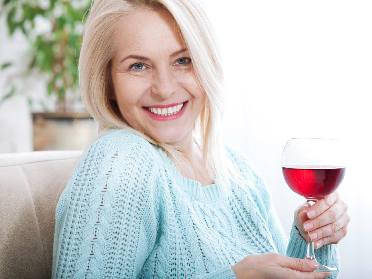 older woman smiling and holding glass of red wine