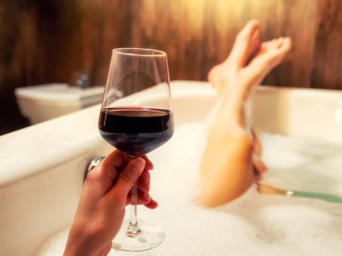 woman sitting in bathtub holding wine glass